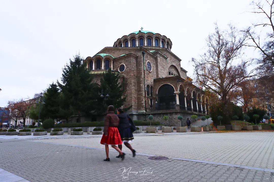 women walking in Sofia city centre by a cathedral in cobblestone streets, Bulgaria