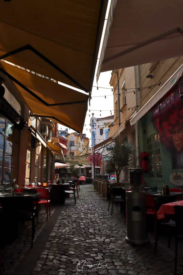 Small cobblestone street in the Plovdiv Kapana Creative District with shops and cafes on the sides bellow colourful houses