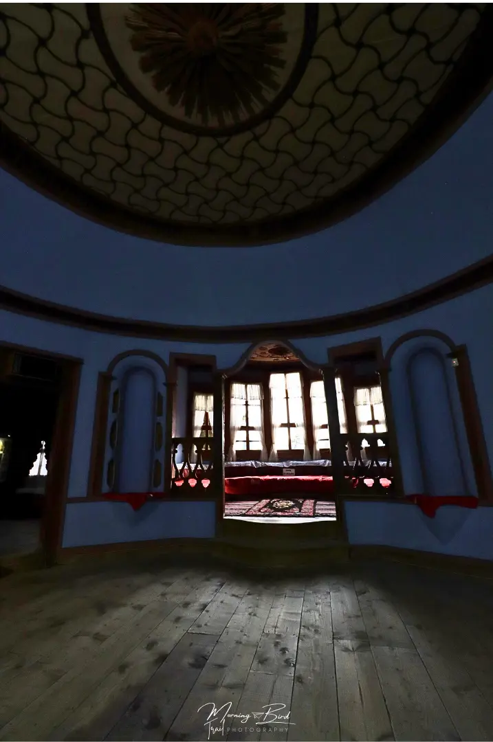 Interior of a traditional bulgarian house - House Museum “Todor Kableshkov” - with wood floor, blue walls, a nice windowed nook and a pattern ceiling in Koprivshtitsa Village, Bulgaria