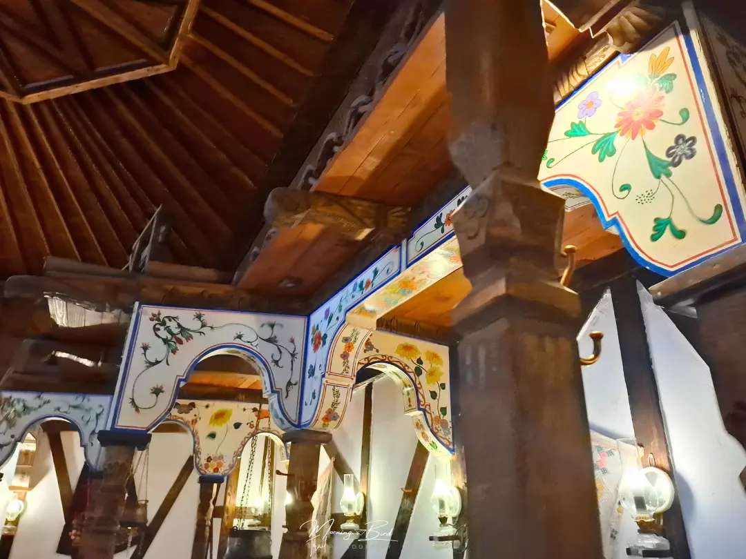 interior of a bulgarian tradition restaurant, with a wood roof and tile walls with colourful drawings and wood columns