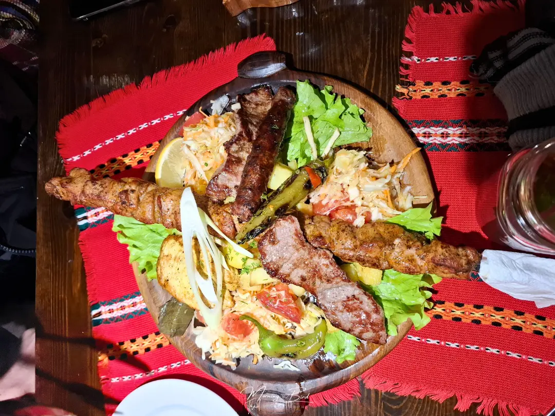 grilled meat plate as traditional bulgarian food on top of red fabric napkins with traditional bulgarian patterns