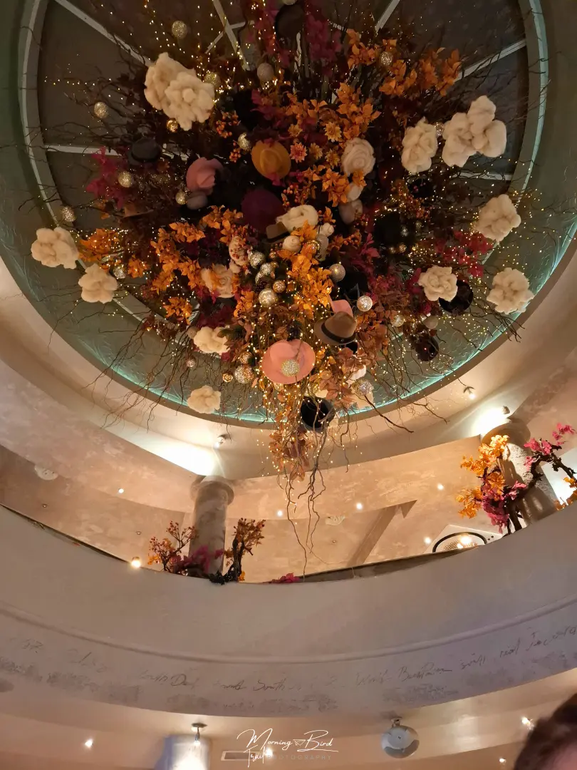 Ceiling of a restaurant in Sofia with flowers and hats decorating it around lights